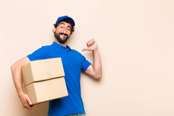 young bearded delivery man with a box - Фото, изображение