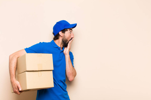 young bearded delivery man with a box - 写真・画像