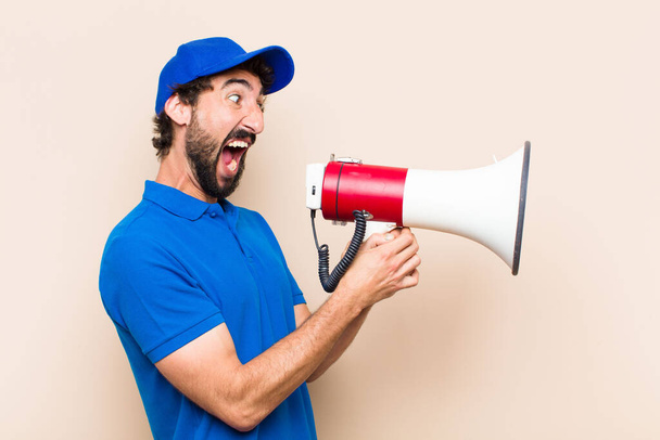 young cool bearded man with a megaphone. delivery man concept - Photo, Image