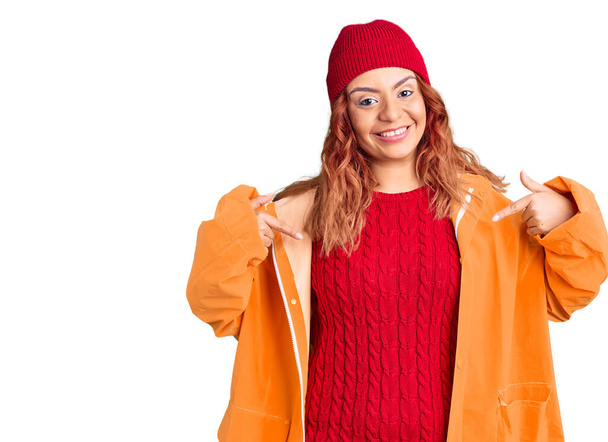 Mujer latina joven vistiendo ropa casual de invierno que se ve confiada con sonrisa en la cara, señalándose con los dedos orgullosos y felices
.  - Foto, Imagen