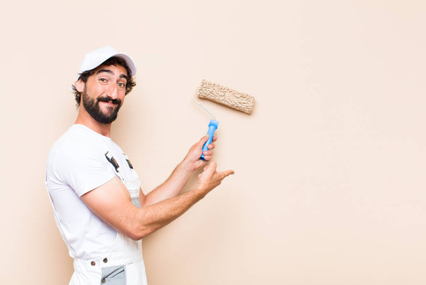 young painter bearded man painting a wall with a apint roller - Foto, imagen