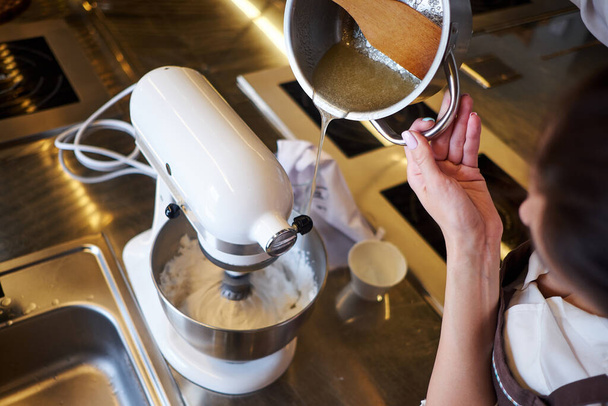 Woman using mixer standing at counter in her apron. Making dessert in pastry - Foto, Imagem