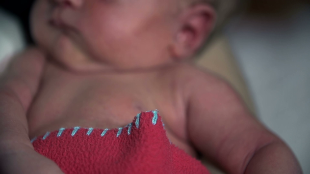 Baby lying on mother's lap while holding her finger - Felvétel, videó