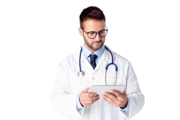 Portrait shot of male doctor using digital table while standing at isolated white background. Copy spcace. - Фото, зображення