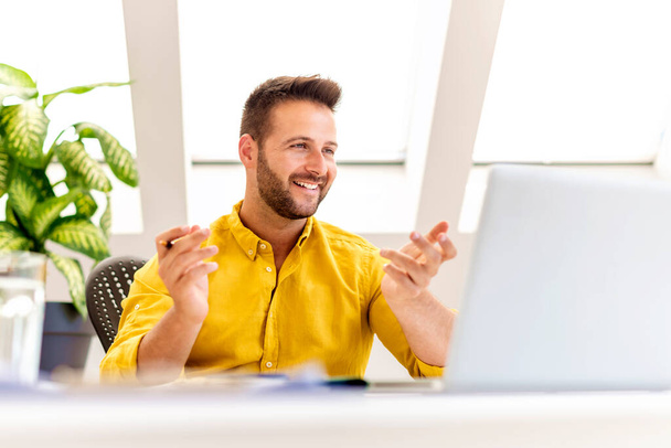 Съемка счастливого бизнесмена, сидящего за своим ноутбуком и обсуждающего и онлайн-встречи в видеозвонке.  - Фото, изображение