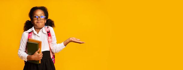 Puzzled African American Schoolgirl Shrugging Shoulders Over Yellow Background, Panorama - Foto, imagen