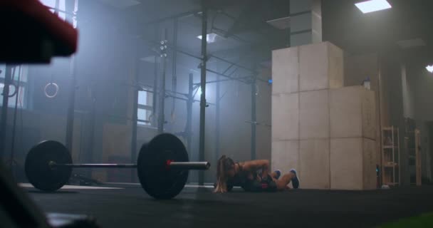 сильная женщина во время тренировки держит отрыжку с тяжелыми гантелями делать толчок ИБП и прыгать в тренажерном зале - Кадры, видео
