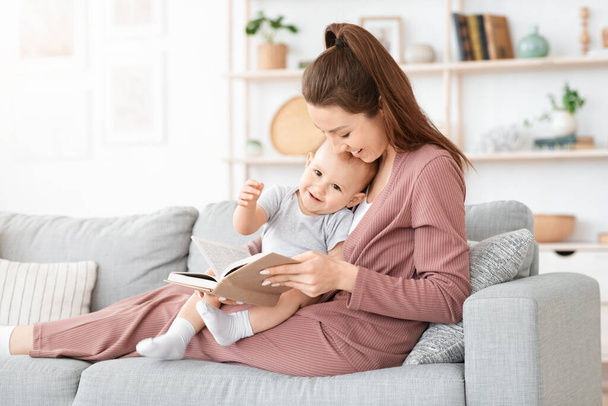 Mother reading book to her cute little toddler son at home - 写真・画像