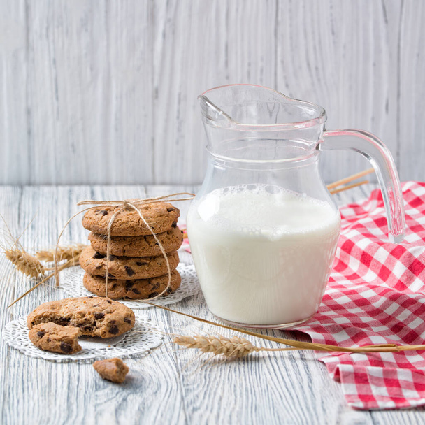 jarro de leite e biscoitos de chocolate no fundo de madeira
 - Foto, Imagem