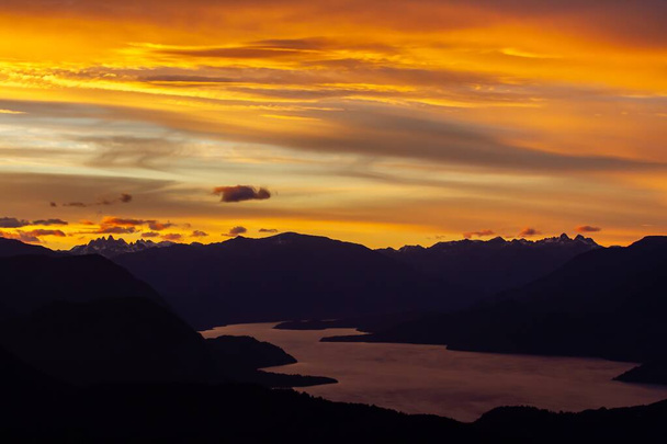 A lake surrounded by hills under a cloudy sky during a beautiful sunset in Patagonia, Argentina - Foto, Bild