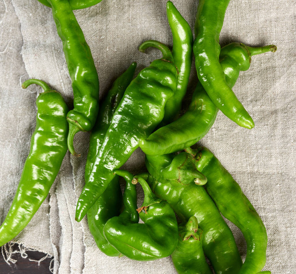 green hot pepper pods on a brown wooden table, top view - 写真・画像