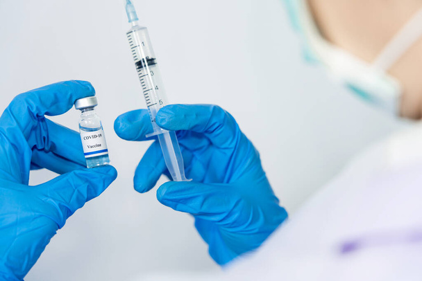 Médecin, scientifique, chercheur main dans les gants bleus ou combinaison de protection se préparant pour les essais cliniques d'injection humaine vaccination covid-19 vaccination contre le coronavirus Concept de risque biologique - Photo, image