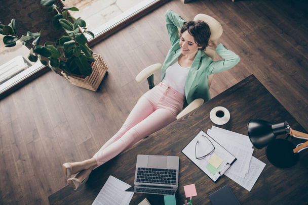 Full size high angle above view photo of beautiful business lady hands behind head eyes closed imagination flight resting house remote work legs on table sit big chair office indoors - Fotó, kép
