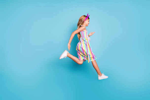 Full length body size profile side view of her she nice attractive trendy cheerful cheery girl jumping running having fun isolated over bright vivid shine vibrant blue color background - Foto, Imagen