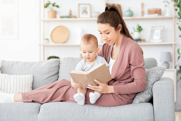 Young Mother And Her Cute Baby Son Reading Book Together At Home - Photo, image