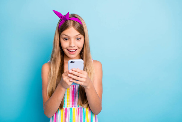 Portrait of positive shocked girl use smartphone read social network news impressed post comment wear stylish dress skirt isolated over blue color background - Фото, зображення