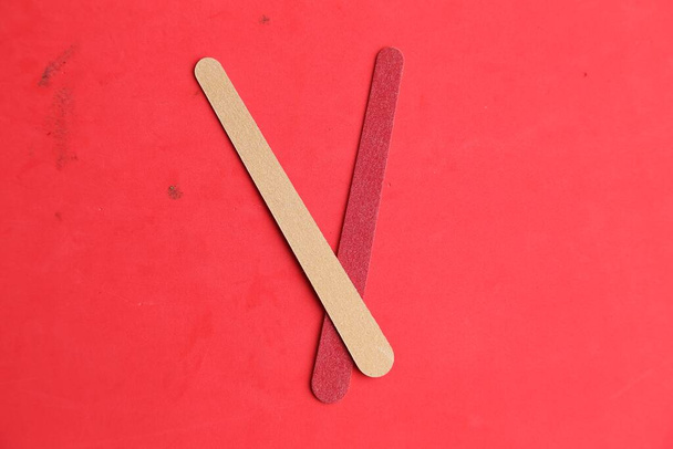 A closeup shot of the two wooden sticks isolated on a red background - 写真・画像