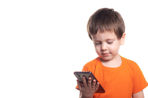 A small boy with a phone on a white background. Boys phone. The children of today . Connection with the child. Benefits and harms of phones . Smartphone for a small child - Foto, imagen
