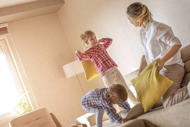 A happy mother having a funny pillow fight with her children - Foto, Imagen