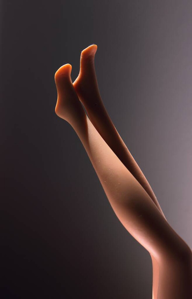 A vertical closeup shot of plastic mannequin's legs with a dark background - Photo, image
