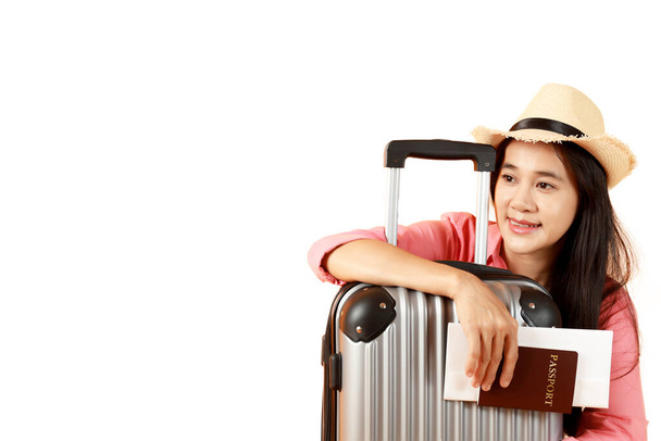 Asyalı uzun saçlı kadınlar Hasır şapka takıyor, elinde pasaport defteri ve fotokopi dolu seyahat çantası ile beyaz arka planda bavulla seyahat etmeye hazır genç bir kız. Yaz tatili konsepti. - Fotoğraf, Görsel