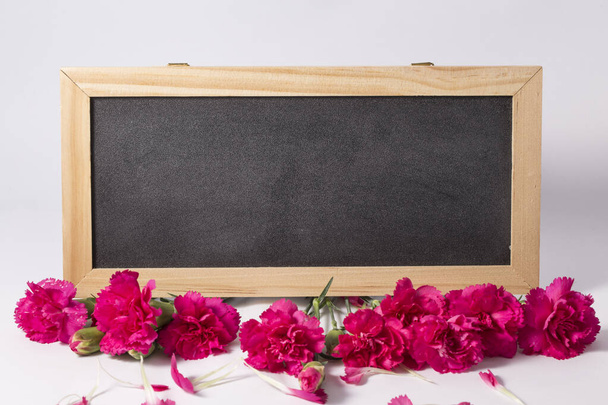 Pink carnation flowers on white background with blank small blackboard - Photo, Image