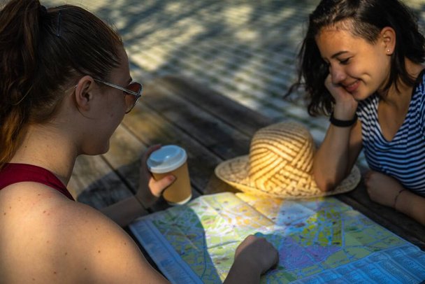 Two Caucasian young female tourists looking at the city map - Foto, Bild