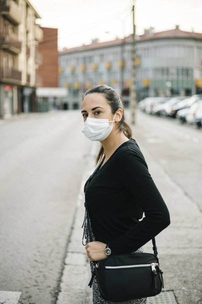 Spaanse vrouw met gezichtsmasker op straat. Levensstijl van het coronavirus - Foto, afbeelding