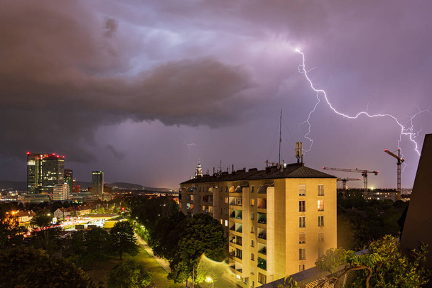 Gewelddadige zomer onweer met enorme bliksem over de Wienerberg City in Wenen met bouwkranen aan de rechterkant van de foto - Foto, afbeelding