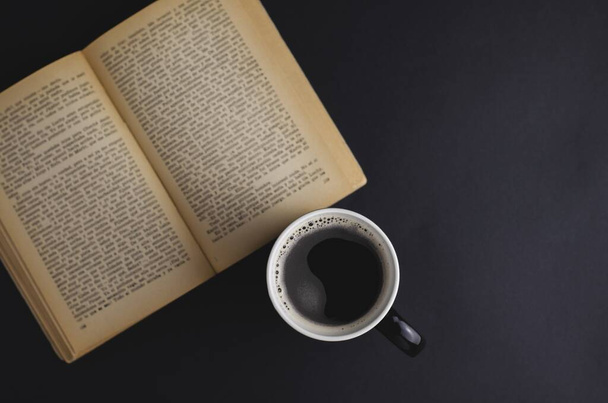 Bir fincan kahve ve açık bir kitabın yüksek açılı çekimi. - Fotoğraf, Görsel