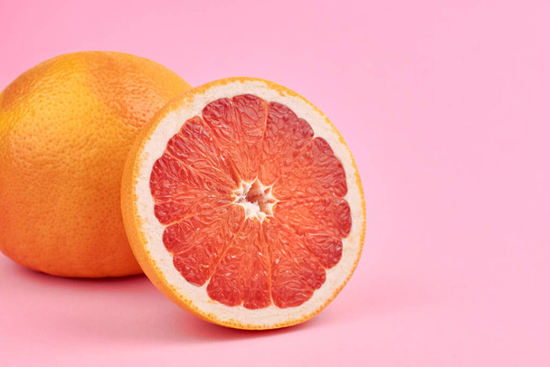 Fresh pink grapefruit citrus fruits on pink background, copy space - Фото, изображение