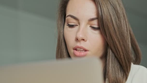 Close up view of Focused pretty brunette woman using laptop computer while sitting by the table at office - Záběry, video