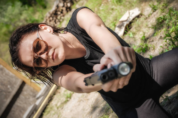 Attractive soldier woman practice shooting and gun point aim to attacker. Close-up pistol pointing front view. Nature outdoor - Photo, image