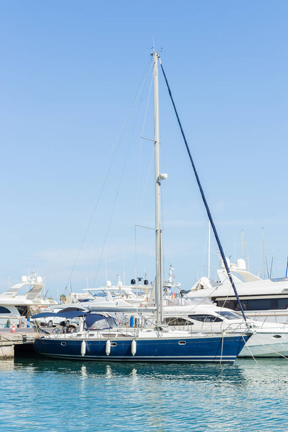 Alicante, Spanje; 15 juli 2020; een blauw-witte boot afgemeerd in de haven omringd door boten op een zomerdag - Foto, afbeelding