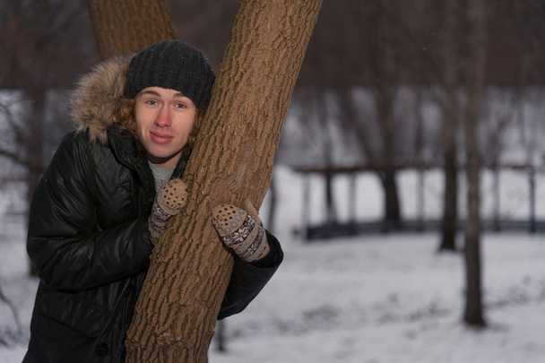 Man stands near the tree in winter park - Zdjęcie, obraz