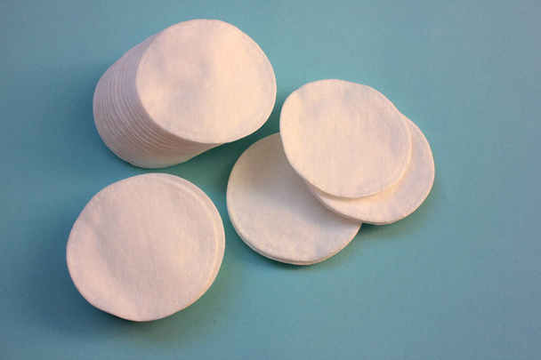 Косметический продукт Хлопчатобумажные прокладки для кожи на синем фоне с копировальным местом. Вид сверху, выборочный фокус - Фото, изображение