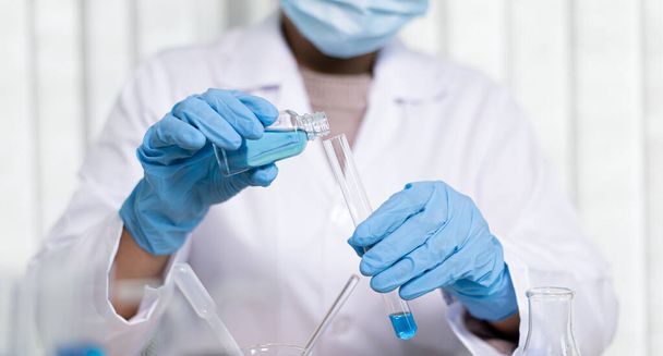 Wissenschaftler tragen blaue chemische Reagenzgläser, um sich in einem wissenschaftlichen Labor auf die Bestimmung der chemischen Zusammensetzung und der biologischen Masse vorzubereiten.. - Foto, Bild