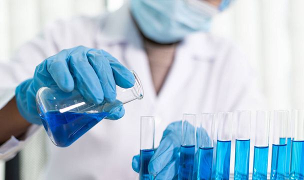 Bilim insanları kimyasal bileşimin ve biyolojik kütlesinin bilimsel bir laboratuvarda, bilim adamlarında ve laboratuar konseptinde tespit edilmesine hazırlanmak için mavi kimyasal test tüpleri taşıyorlar.. - Fotoğraf, Görsel