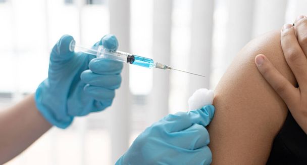 医師は、ウイルスの拡散を防ぐために抗生物質や新しい抗体を持つ女性をワクチン接種しています,感染症に対するワクチン接種は続けます - 写真・画像