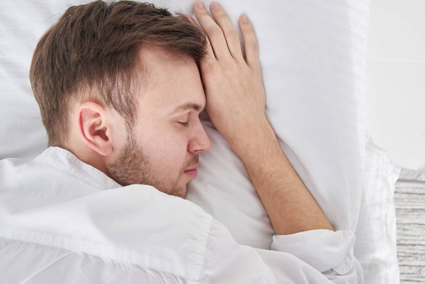 Close-up portrait of sleeping brunette man on white pillow - Foto, Imagem