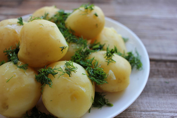 Tradycyjne szwedzkie Midsummer żywności nowe ziemniaki z koperkiem na starym drewnianym stole pokładzie. Całe ziemniaki gotowane na białym talerzu - Zdjęcie, obraz