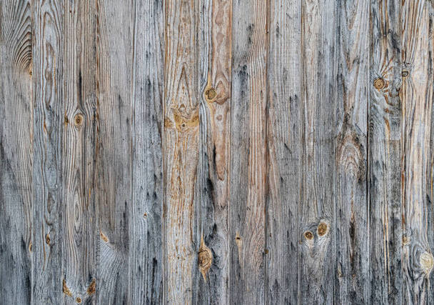 An old and rotten wooden fence. The texture of vertical boards with bitches. Old boards. - Zdjęcie, obraz