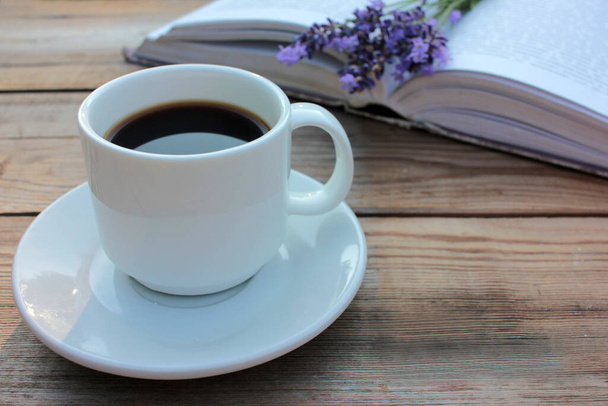 Bir fincan kahve, kitap ve bahçedeki ahşap masada cam vazoda mor yaz çiçekleri. Seçici odaklanma. Boşluğu kopyala - Fotoğraf, Görsel