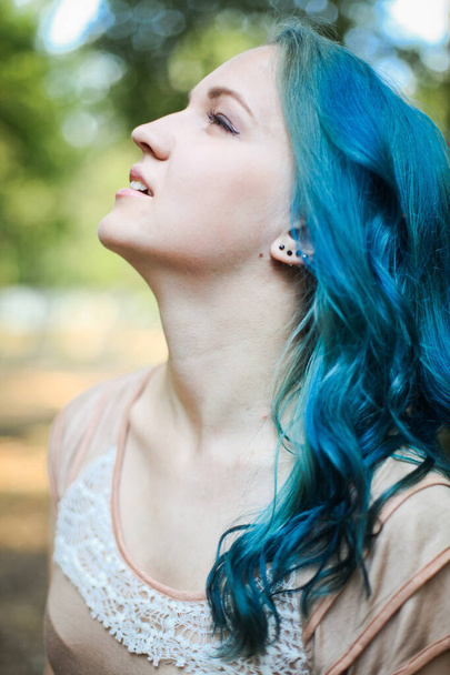 夏のサニーフォレストで青い髪の若い夢のようなLGBTの女の子。矢で中性化粧をした美人. - 写真・画像