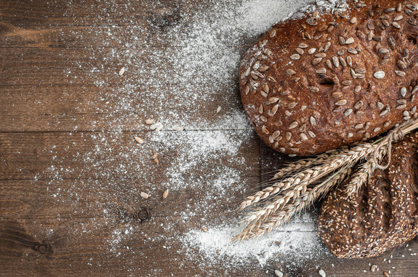 Zwei verschiedene Brote Vollkornbrot. Zusammensetzung mit Mehl und Weizenähren. - Foto, Bild