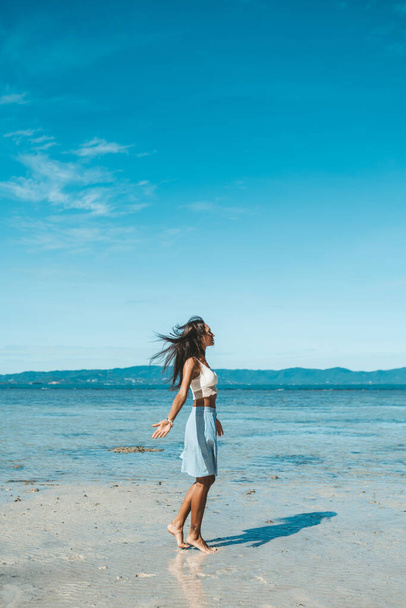 Woman in blue skirt and white top walking at the beach. Paradise beach - Foto, Imagem