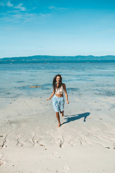 Nainen sinisessä hameessa ja valkoinen toppi kävelemässä rannalla. Paratiisin ranta - Valokuva, kuva