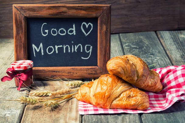Frame with Good morning text and fresh croissants, jam and spikelets on wooden background - Photo, Image