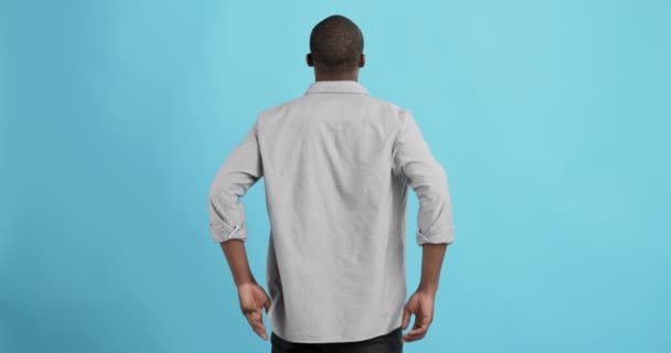 Musta mies pitää käsiään selkänsä takana, venyttelee selkärankaa - Materiaali, video