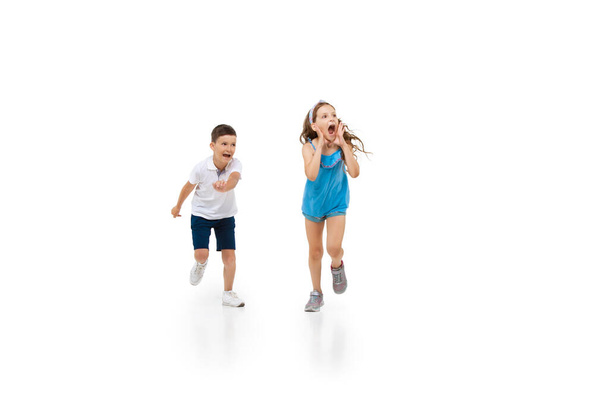 Happy little caucasian girl and boy jumping and running isolated on white background - Φωτογραφία, εικόνα